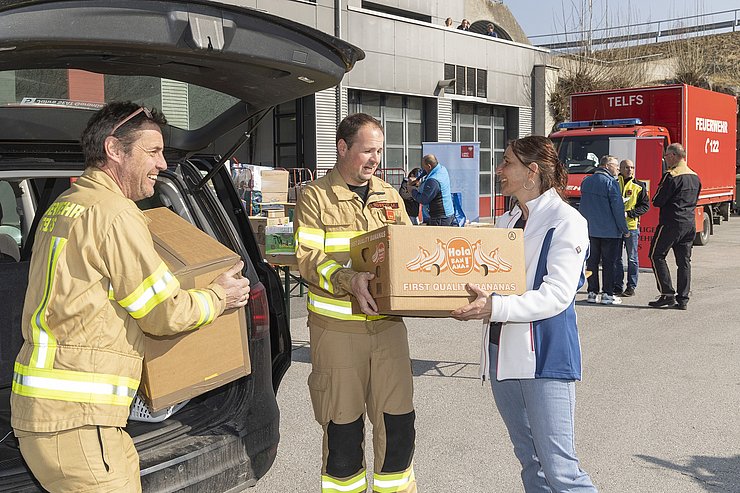 © Land Tirol/Die Fotografen Frau, die ein Paket bei den Feuerwehren abgibt.