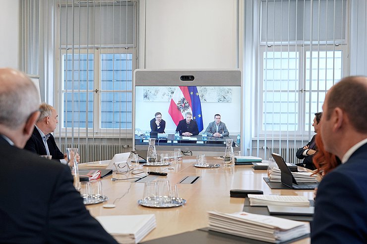 © Land Tirol/Neuner Am Ende eines ovalen Tisches steht ein Bildschirm.