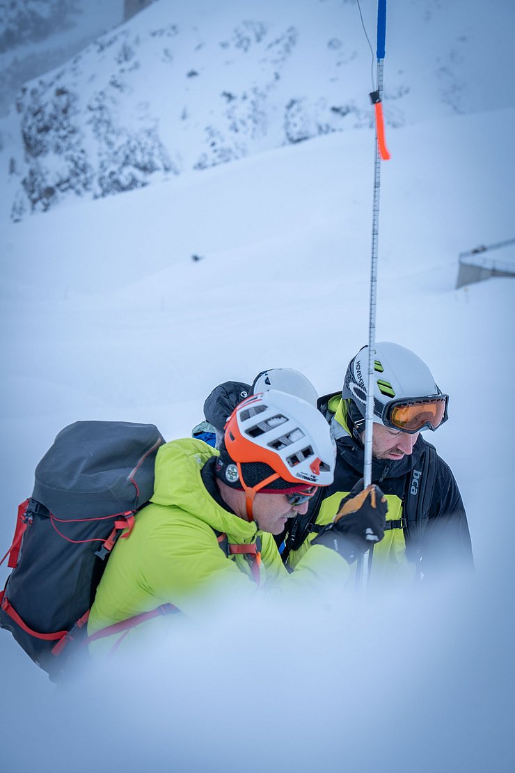 Männer untersuchen Schneedecke