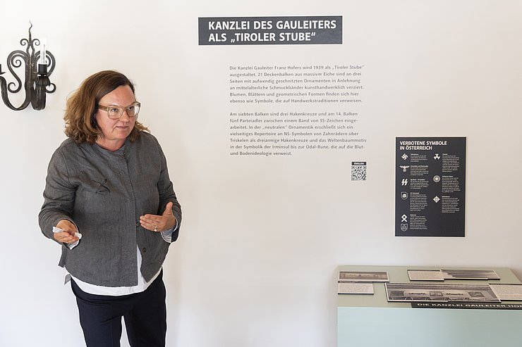 Eine Frau vor einer Wand im Ausstellungsraum, die beschriftet ist.