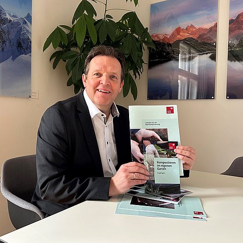 Zumtobel hält Broschüre in die Kamera