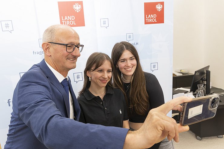 © Land Tirol/Die Fotografen Der Landeshauptmann macht ein Selfie mit zwei Schülerinnen.