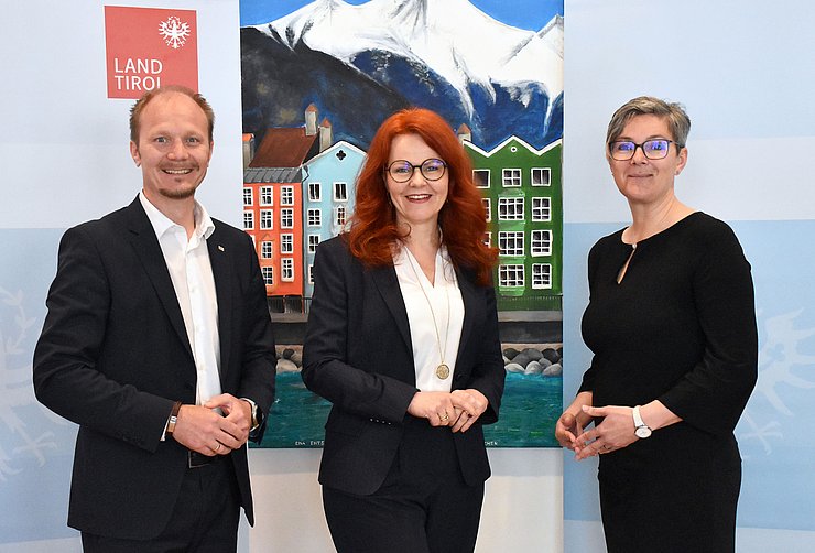 © Land Tirol/Jansenberger Gruppenfoto der Besprechung im Stadtsenat. Vizebürgermeister Johannes Anzengruber, Landesrätin Cornelia Hagele und Kathrin Eberle - die Vorständin der Abteilung Pflege des Landes - stehen im Sitzungssaal vor einem Gemälde der Stadt Innsbruck.