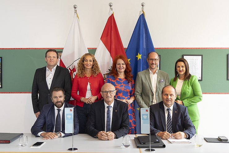 Alle Mitglieder der Tiroler Landesregierung auf einem Gruppenbild mit der österreichischen, tiroler und europäischen Flagge im Hintergrund.