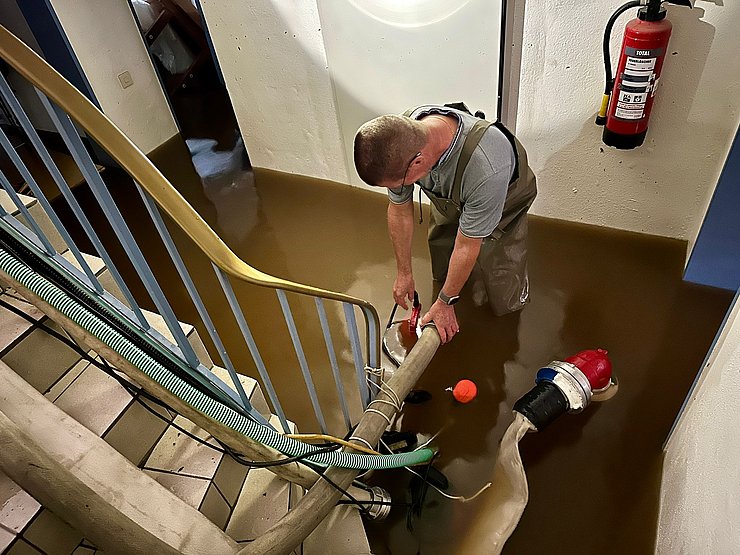Ein Feuerwehrmann pumpt einen Keller aus.