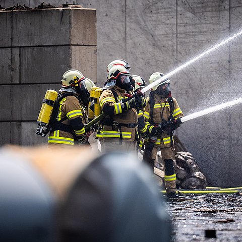 Im Bild: Vier Feuerwehrleute die einen Brand löschen auf einem Recycling-Areal. Knapp 1.000 Einsatzkräfte waren innerhalb der vier Tage beim Großbrand im Einsatz. 
