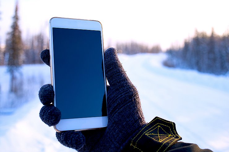 © Shutterstock Hand hält Mobiltelefon in einer winterlichen Umgebung
