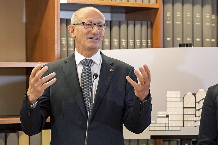 © Land Tirol/Die Fotografen LH Mattle steht vor einem Bücherregal hinter einem Rednerpult