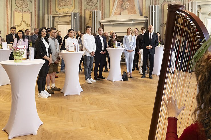 Mehrere Menschen hören einer Musikantin beim Spielen zu.