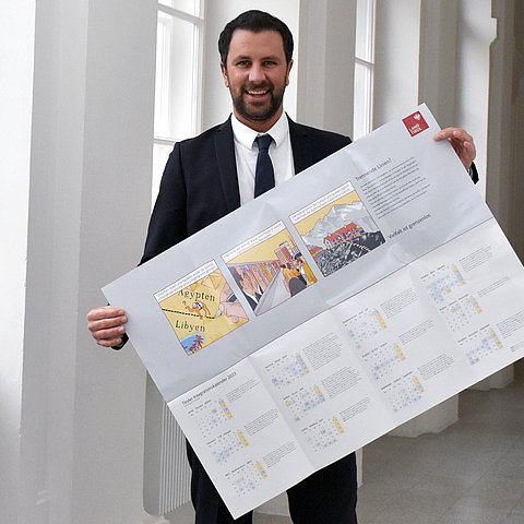 LHStv Dornauer hält ein geöffnetes Exemplar des Tiroler Integrationskalenders in den Händen.