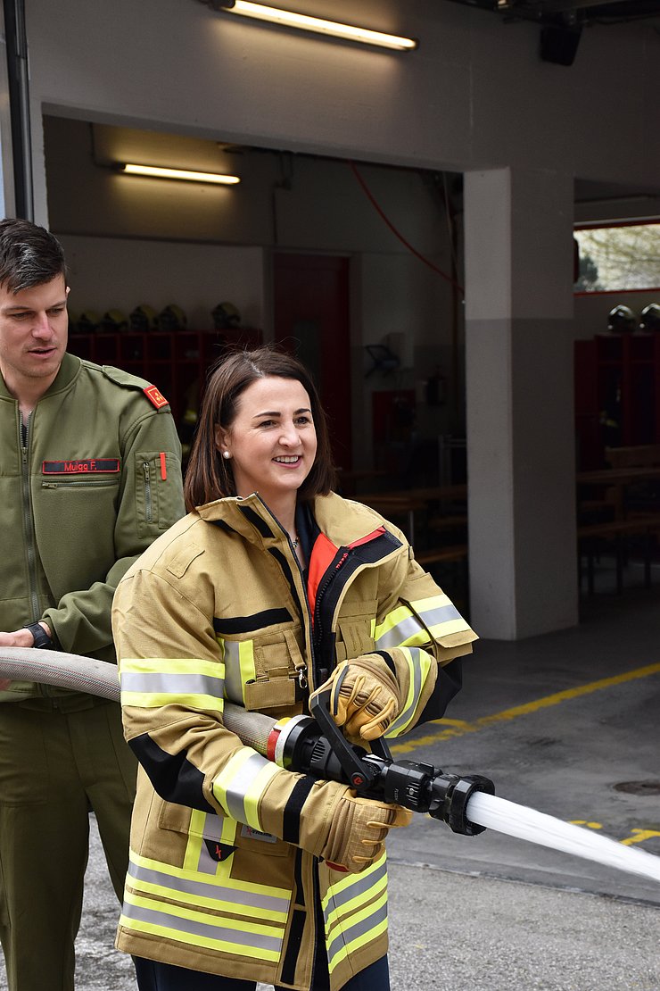 Mair mit Feuerwehrjacke hat Schlauch in der Hand aus dem Wasser kommt