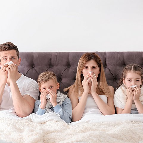 Familie liegt verkühlt im Bett