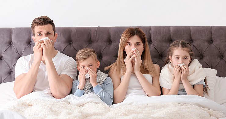 Familie liegt verkühlt im Bett