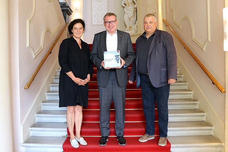 Gruppenfoto; LR Tratter hält Gestaltungsleitfaden in Händen