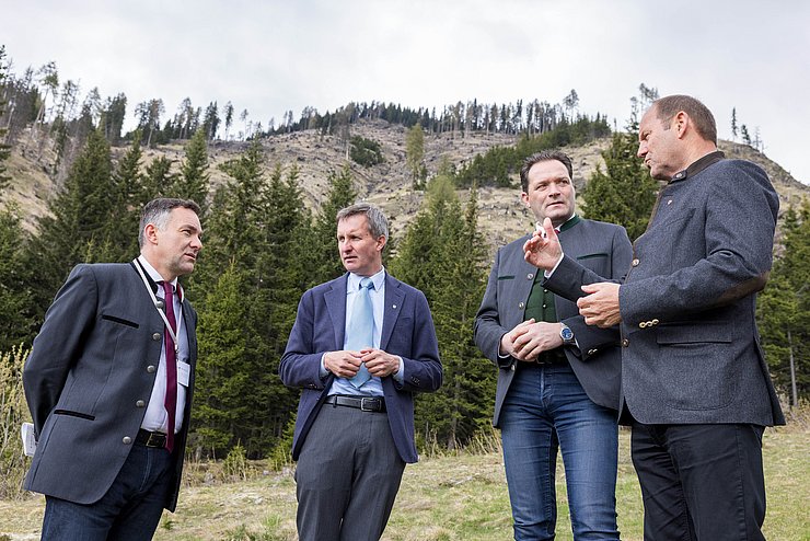 © Land Tirol/Groder Personen im Gespräch - dahinter Wiese, Wald und Berg