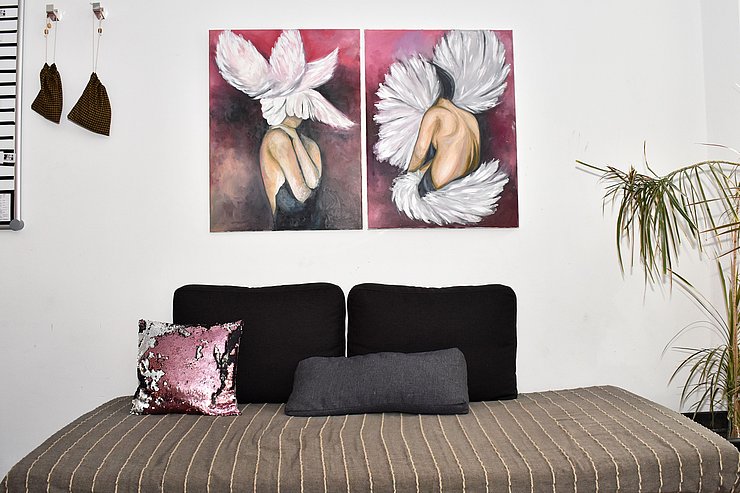 Couch mit Kissen, darüber zwei Bilder