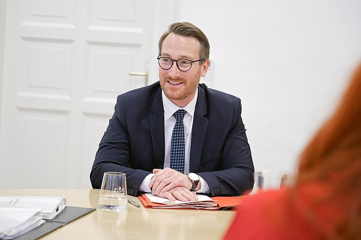 Ein Mann sitzt an einem Tisch und lächelt.