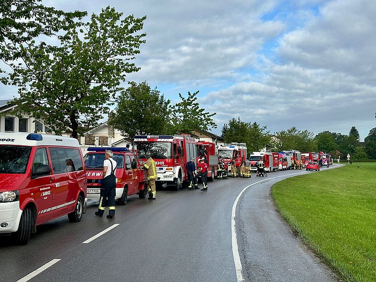 Auf einer Straße stehen mehrere Feuerwehrfahrzeuge hintereinander.