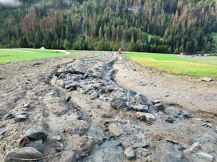 Foto von Mure über Feld; im Hintergrund die Straße