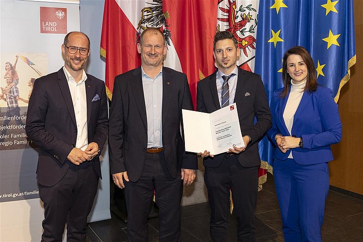 vier Personen mit Urkunde