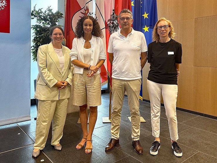 Gruppenfoto, Personen nebeneinander im Großen Saal des Landhauses, vor Fahnen