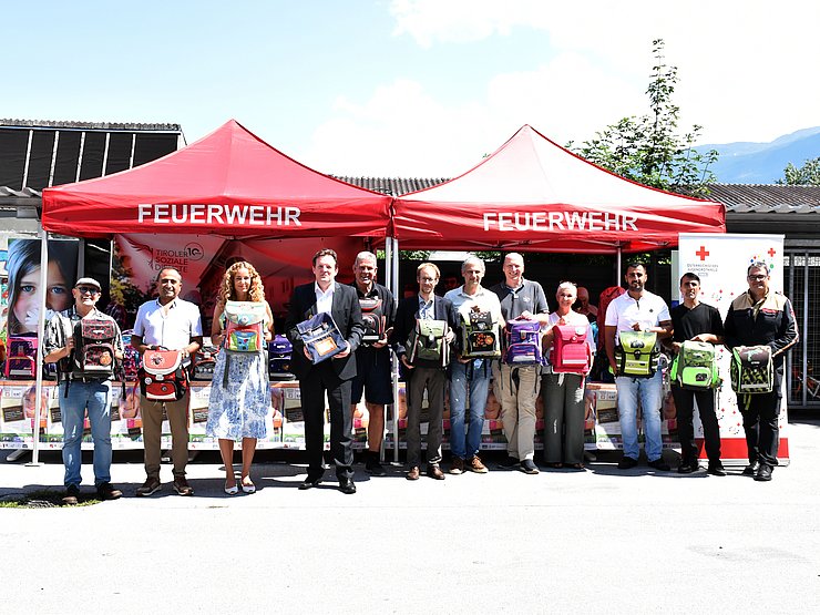 Viele Menschen in einer Reihe halten jeweils eine SChultasche
