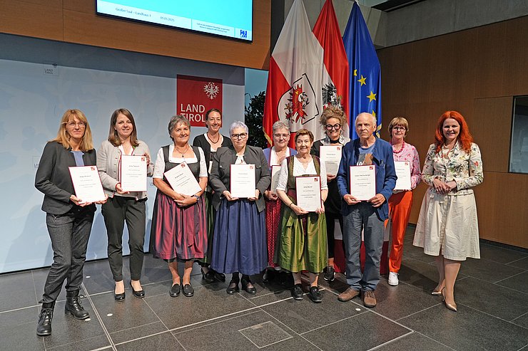 © Land Tirol/Reiter Mehrere Menschen posieren vor Flaggen.