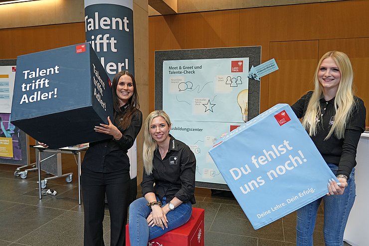 Drei Frauen halten große Würfel in der Hand.