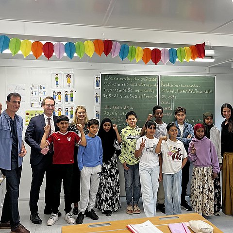 Mehrere Menschen stehen vor einer Schultafel.