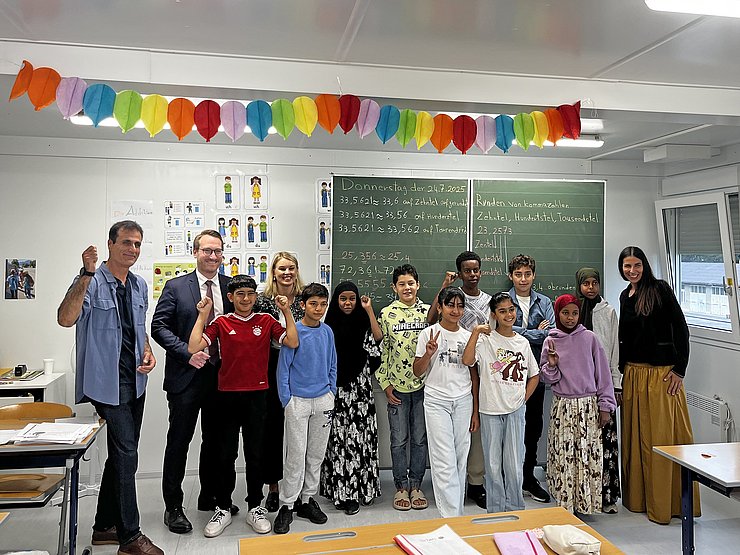 Mehrere Menschen stehen vor einer Schultafel.