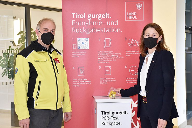 LRin Annette Leja und Elmar Rizzoli vor Rollup "Tirol gurgelt." und Box für Gurgeltests