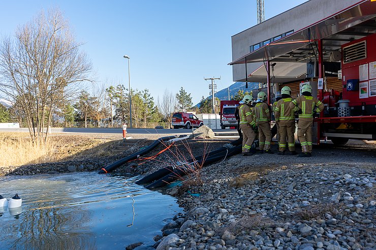 Pumpe bei See stehend; Feuerwehrleute bedienen Pumpe