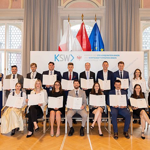 Gruppenbild mit insgesamt zwanzig Personen, bis auf drei halten alle davon eine Urkunde.