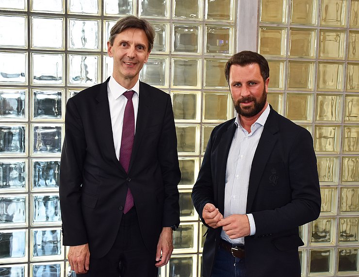 Peter Huber vom Bundesministerium für europäische und internationale Angelegenheiten und Landeshauptmann-Stellvertreter Georg Dornauer zusammen vor einer gekachelten Glaswand.
