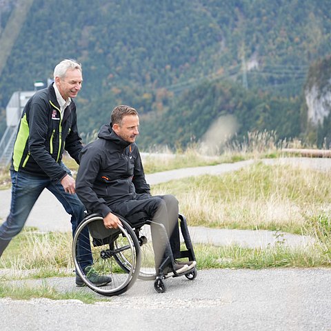 zwei Männer, einer im Rollstuhl