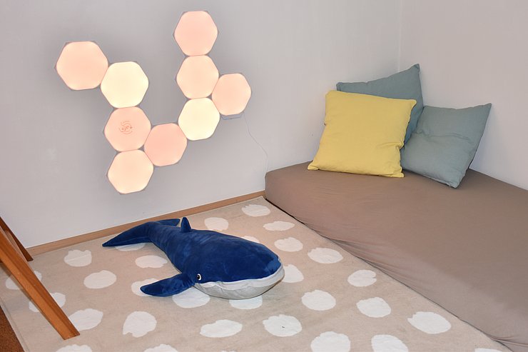 Spielraum: an der Wand sind rautenförmige Lichter, am Boden eine Matratze und Polster sowie ein Wal-Kuscheltier