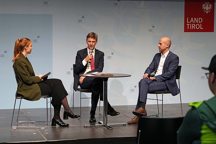 © Land Tirol/Huber Personen sitzen um Tisch, Huber spricht