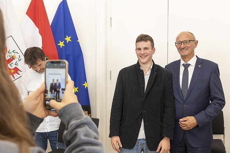 Der Landeshauptmann und ein Schüler werden mit einer Handykamera fotografiert.
