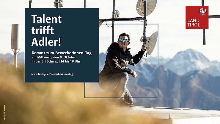 Ein Mann mit Sonnenbrille kniet vor einem Sendemasten auf einem Berg.