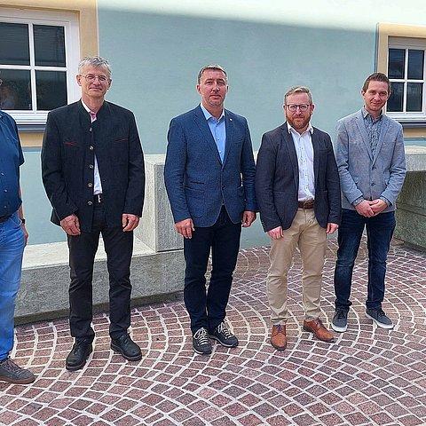 Gruppenfoto der 6 Personen stehend vor hellblauer Hauswand