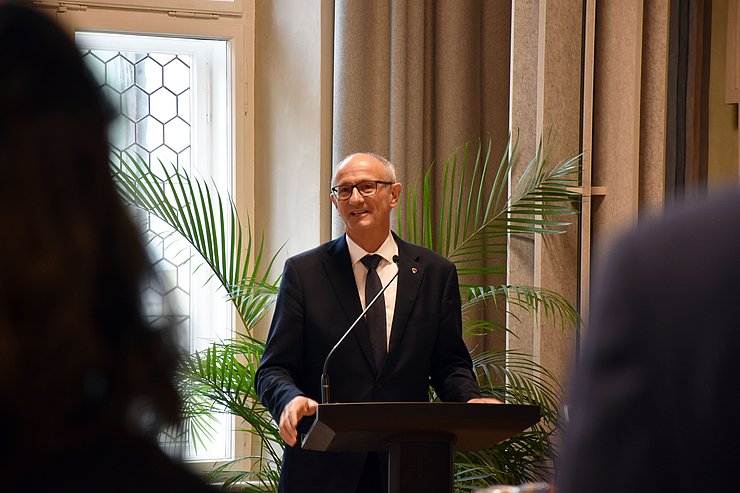 Mann mit Brille steht vor Rednerpult und spricht