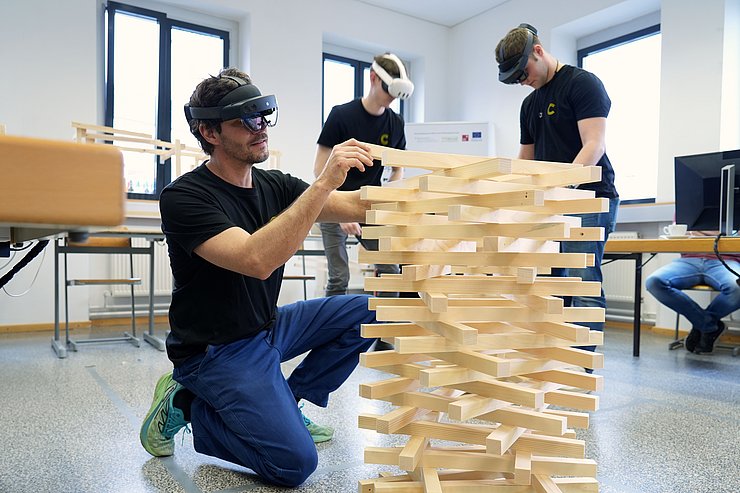 © Land Tirol/Krepper drei Personen mit VR-Brille bauen einen Holzturm