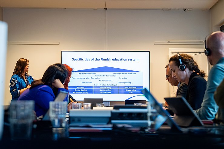 © Land Tirol/Christanell Besprechungszimmer mit Menschen, die am Tisch miteinander reden. Im Hintergrund ist eine Präsentation zu sehen.