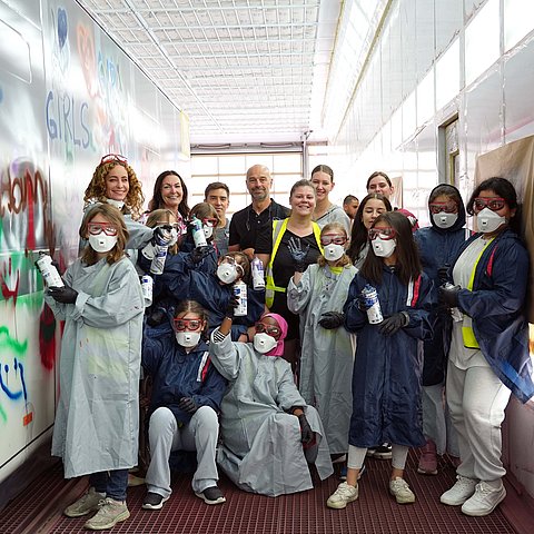 Gruppenfoto von Landesrätin Pawlata und einer Volksschulklasse neben einem bemalten Bus.