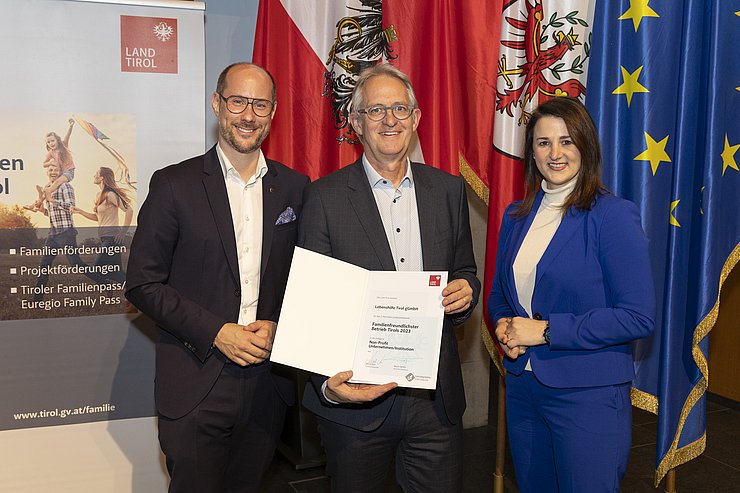 drei Personen mit Urkunde