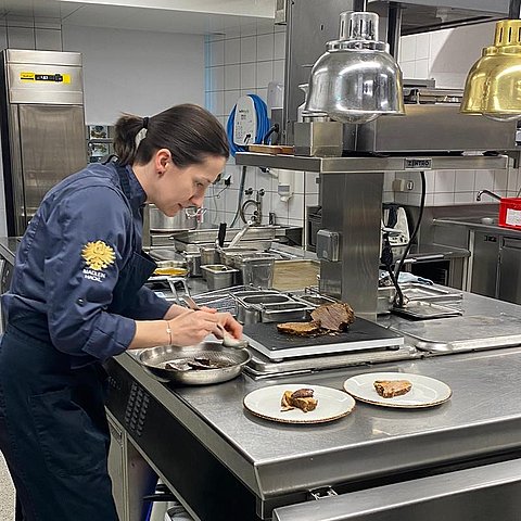 Köchin richtet Gericht an (in Küche)