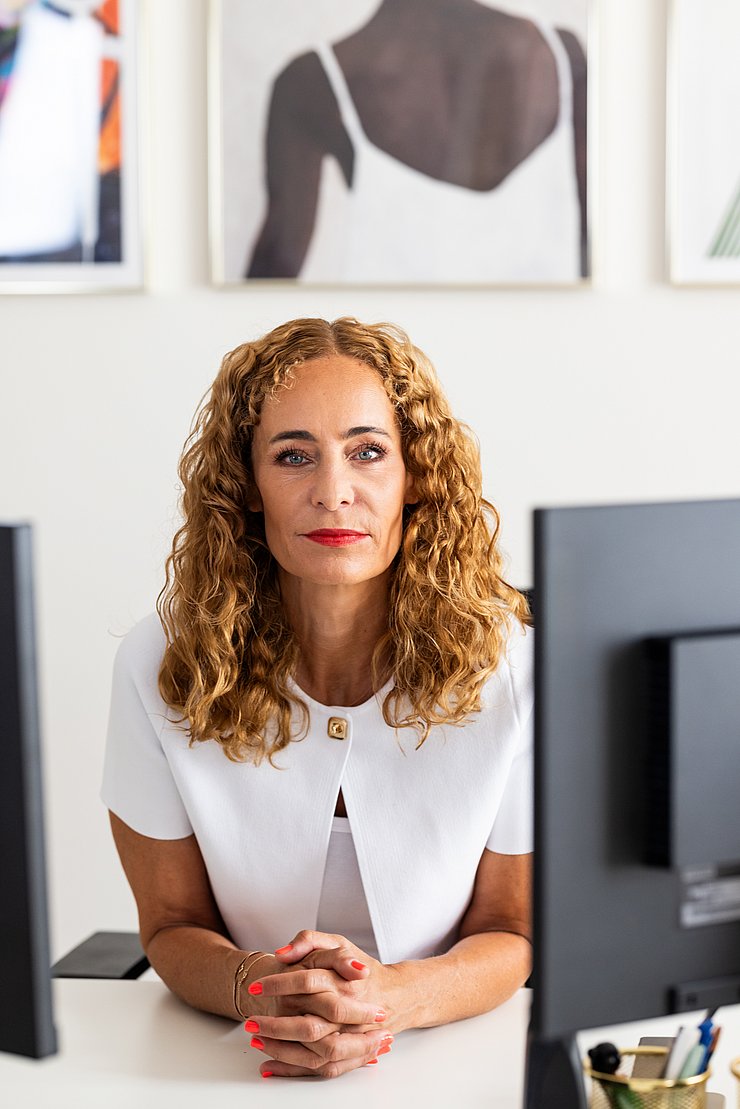 Porträtfoto: LRin an Schreibtisch, blickt in Kamera