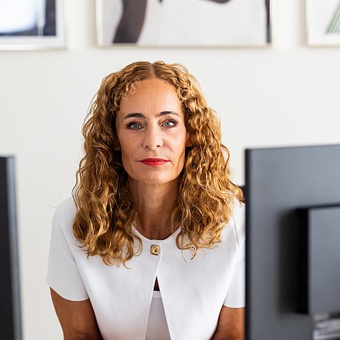 Porträtfoto: LRin an Schreibtisch, blickt in Kamera