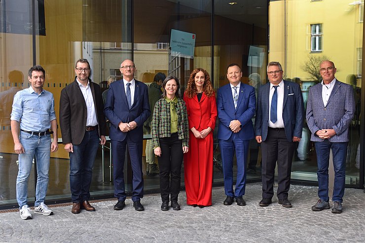 Gruppenfoto - Personen stehen nebeneinander im Freien vor Glaswand