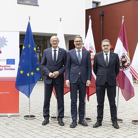 Personen stehen nebeneinander, vor Fahnen und Euregio Roll-up